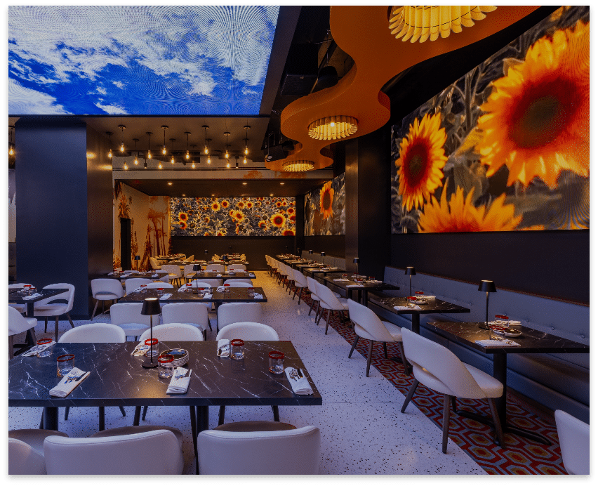 Planet Hollywood NYC dining room featuring sunflower projections and sculptural ceiling lights.