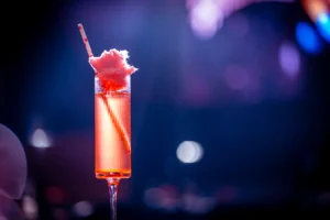 Pink champagne cocktail topped with cotton candy in a flute glass.