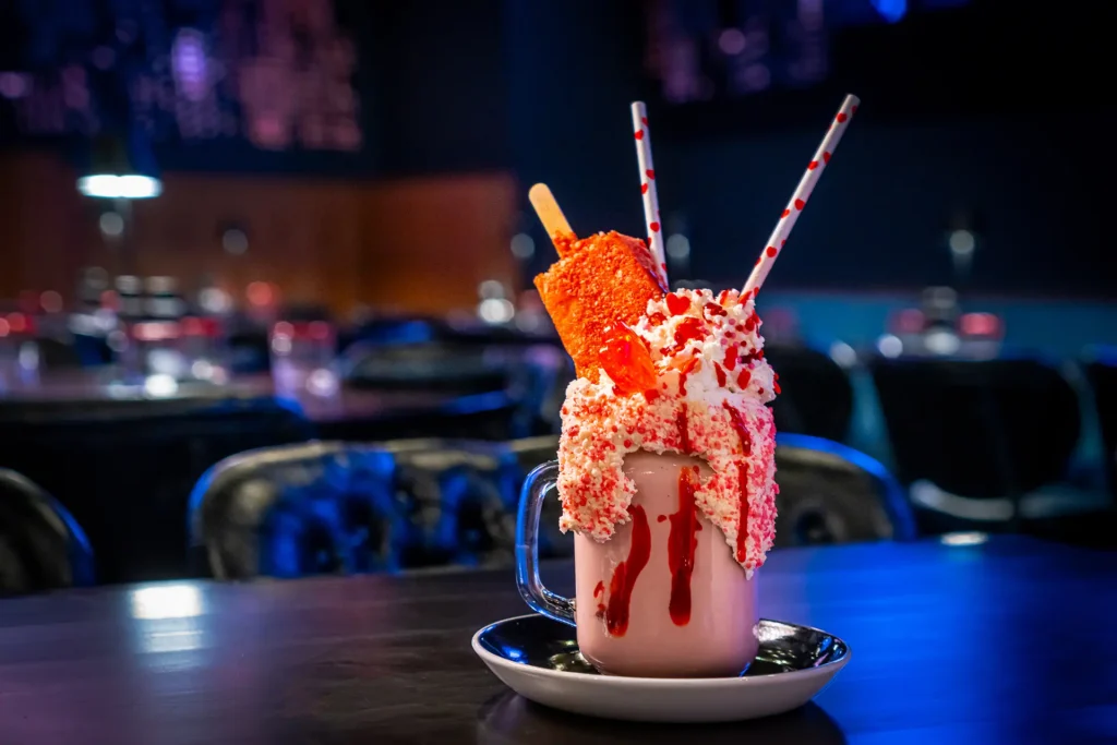 Strawberry shortcake shake topped with whipped cream, candy sprinkles, and a cookie.