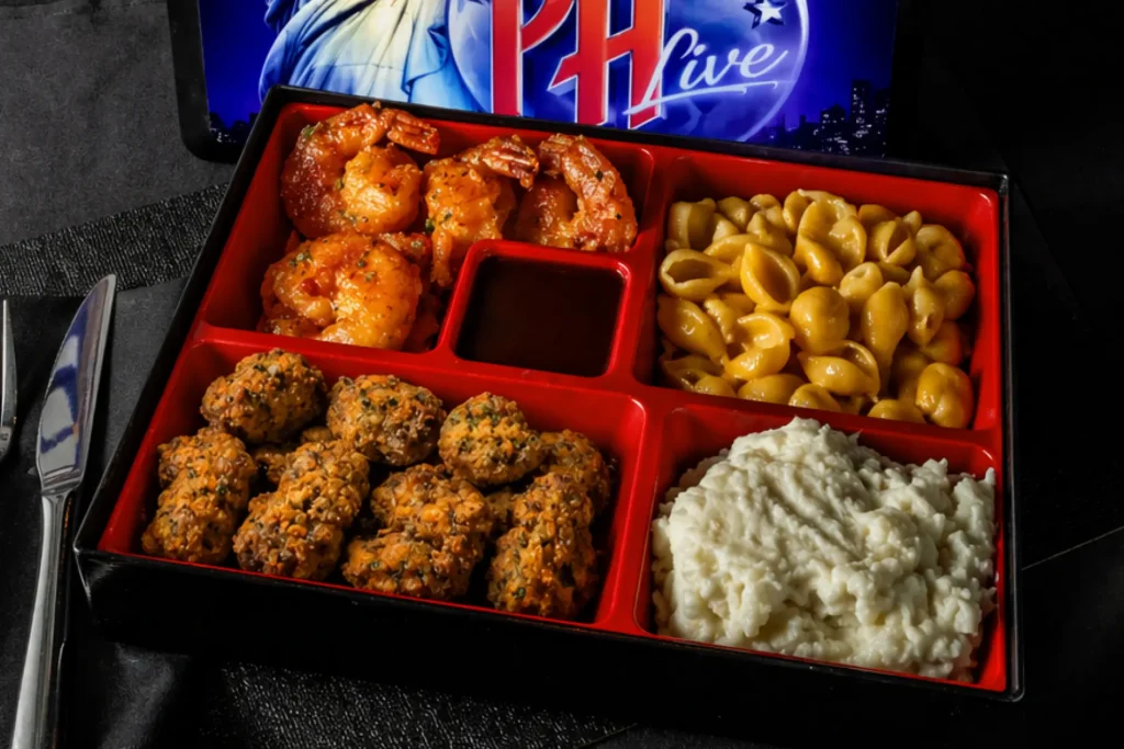 Power Box featuring fried steak tips, sweet chili fried shrimp, mac and cheese, creamy mashed potatoes, and dipping sauce in a divided tray at Planet Hollywood NYC.