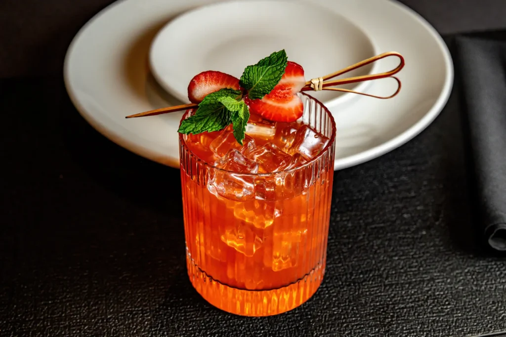 Strawberry cocktail with fresh mint and sliced strawberries over ice in a rocks glass at Planet Hollywood NYC