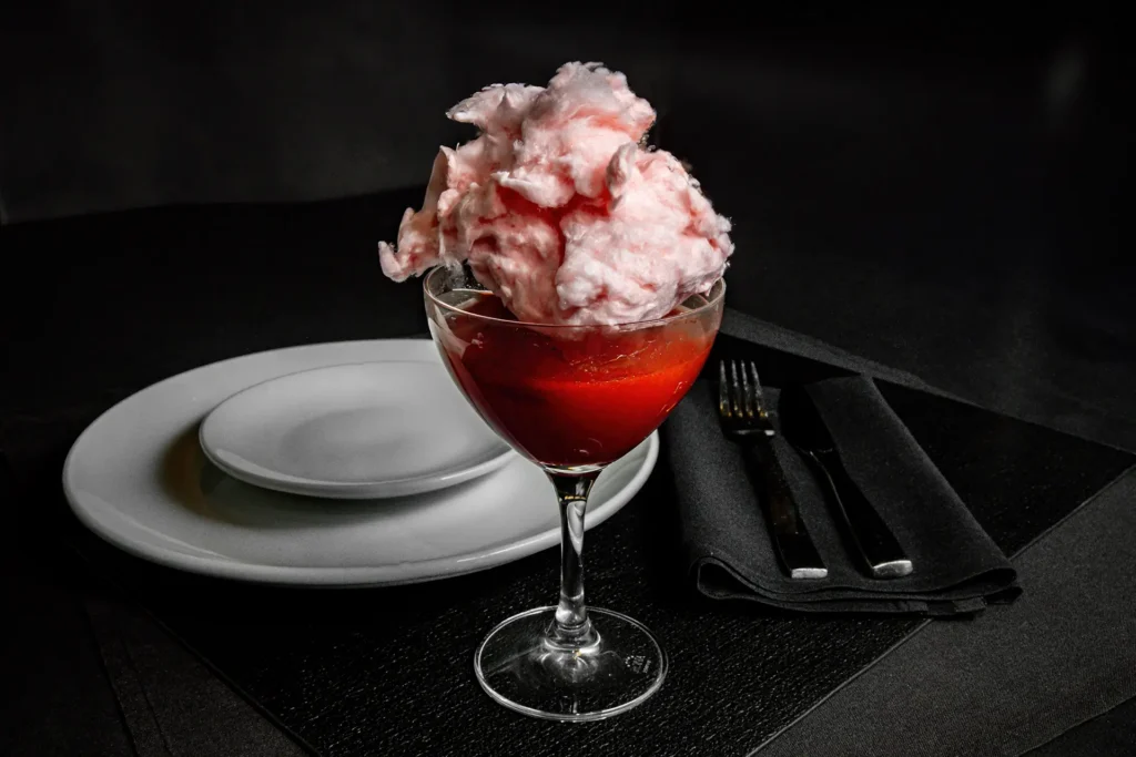 Cocktail topped with pink cotton candy in a martini glass at Planet Hollywood NYC