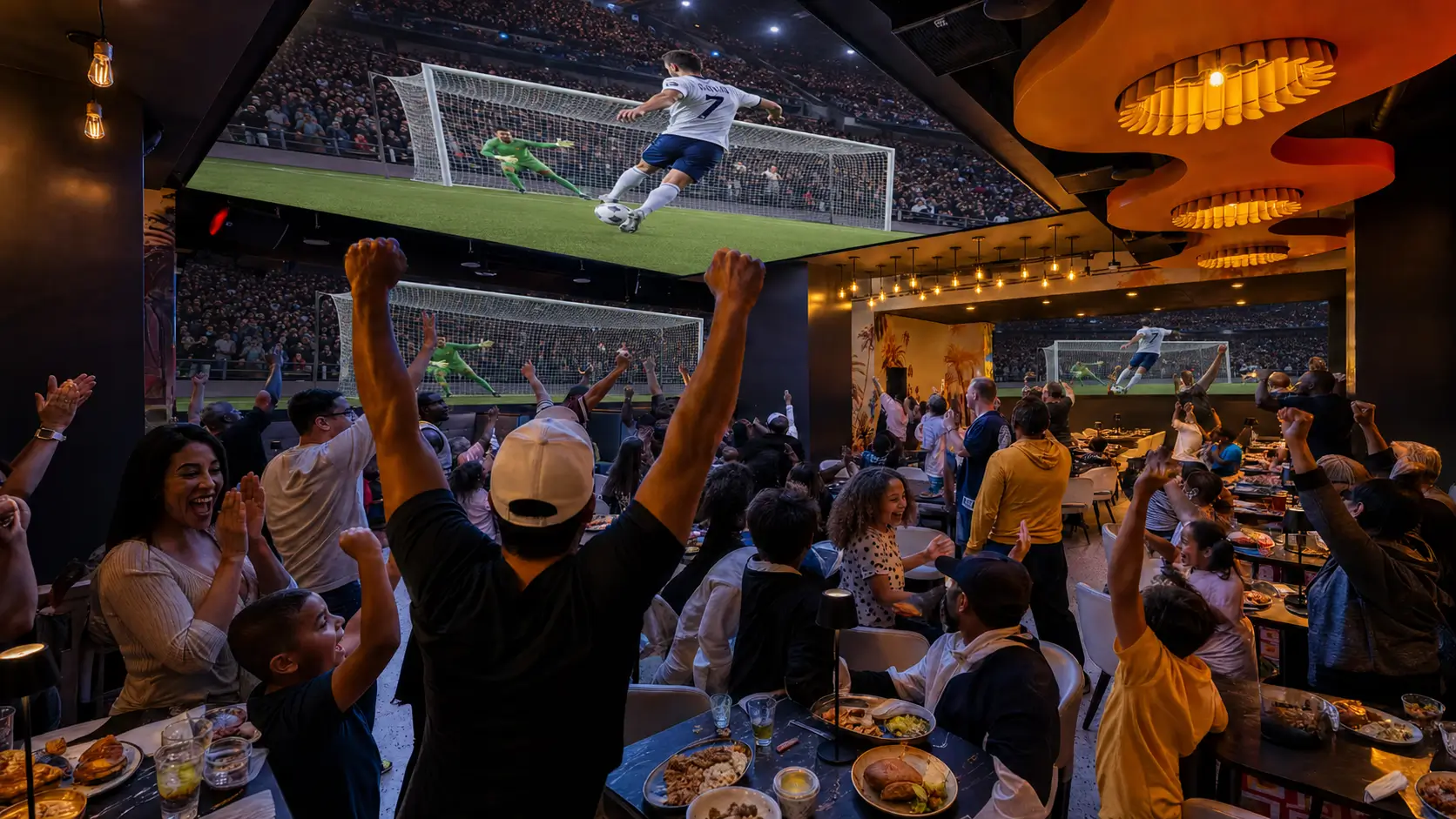 Crowd cheering inside Planet Hollywood NYC while watching a soccer match on massive wall-to-wall screens.